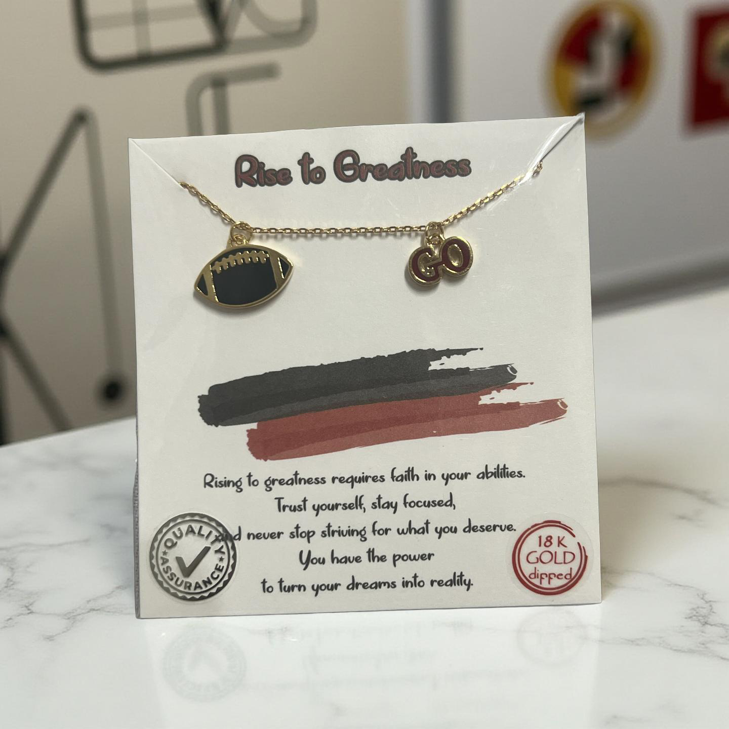 Necklace with football charm and gold accents on a decorative card with text and graphics.